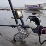 A fishing boat is in the water near some equipment.