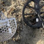 A metal detector and a metal object in the sand.