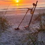 A metal detector on the beach at sunset.